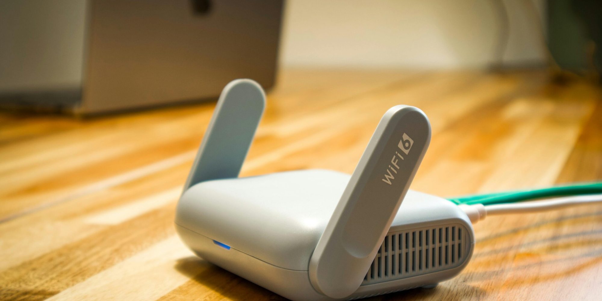 A sleek WiFi 6 router with antennas and cable on a wooden desk, perfect for modern home networks.